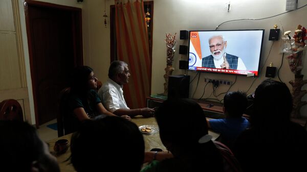 An Indian family watches Indian prime minister Narendra Modi addressing the nation on a television - Sputnik India