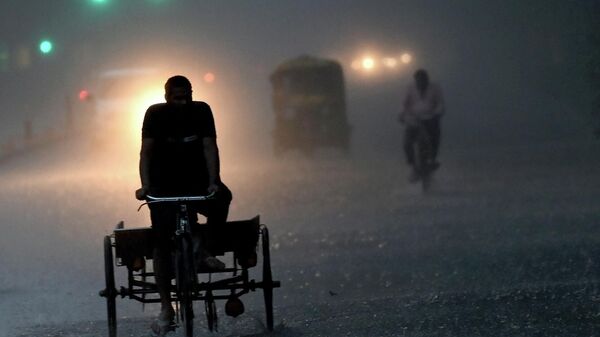 A man rides his cart along a street amid torrential rain in New Delhi on July 15, 2023. - Sputnik India