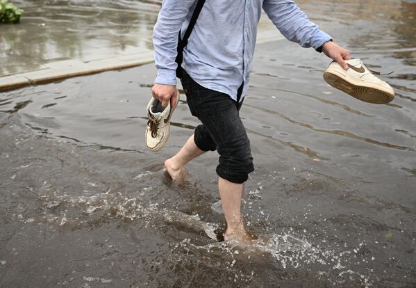 मास्को में भारी बारिश के कारण पानी से भरी सड़क पर एक राहगीर।  - Sputnik भारत