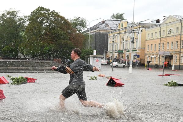 मास्को में भारी बारिश के कारण पानी से भरी सड़क पर एक युवक। - Sputnik भारत