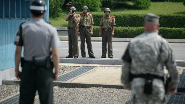 North Korean soldiers (C) take photos towards a South Korean soldier (L) and a US soldier (R) standing before the military demarcation line (lower C) seperating North and South Korea within the Joint Security Area (JSA) at Panmunjom on July 27, 2014 - Sputnik भारत