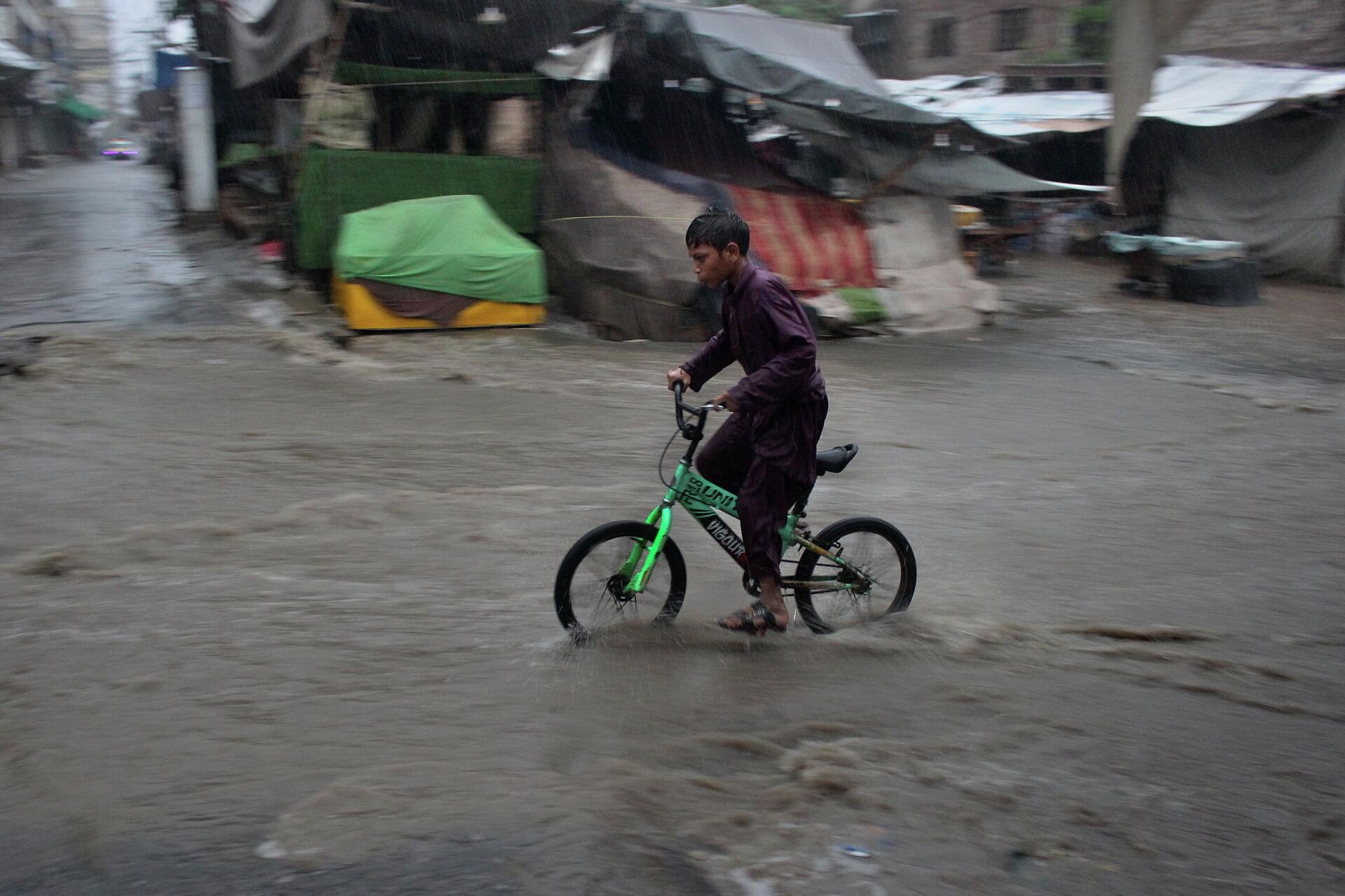 A boy on a bicycle makes his way through a flooded street during heavy rainfall, in Peshawar, Pakistan, Saturday, July 15, 2023. - Sputnik India, 1920, 08.09.2023