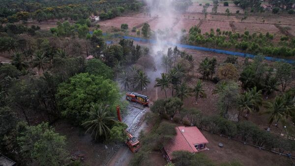 In this aerial photograph, a borewell rig spews dust cloud while drilling a tube-well as a water source inside a residential layout in Bangalore on April 9, 2022.  - Sputnik भारत