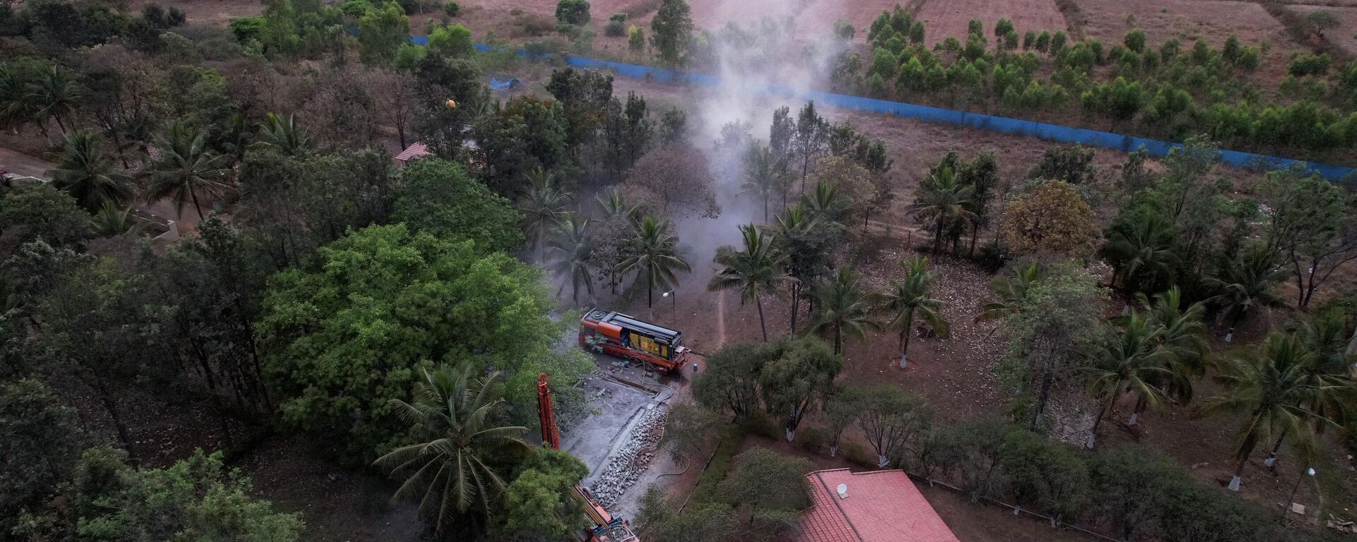 In this aerial photograph, a borewell rig spews dust cloud while drilling a tube-well as a water source inside a residential layout in Bangalore on April 9, 2022.  - Sputnik भारत, 1920, 23.07.2023
