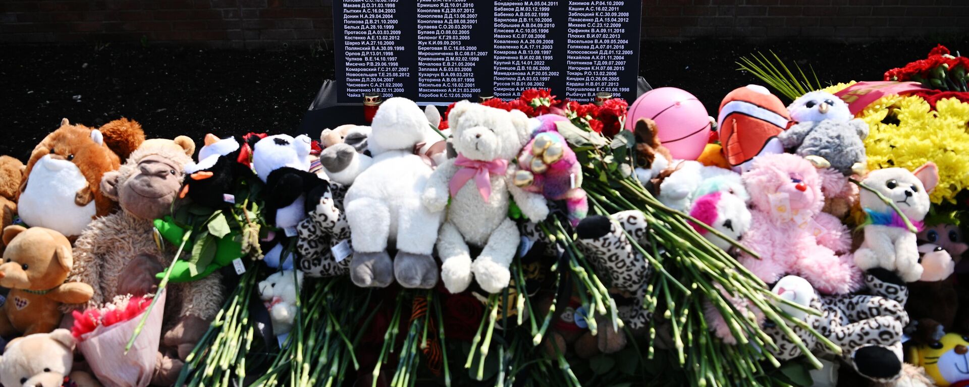 Flowers and toys stacked in front of the Donbass victims' memorial on a square in the Donetsk People's Republic - Sputnik India, 1920, 27.07.2023