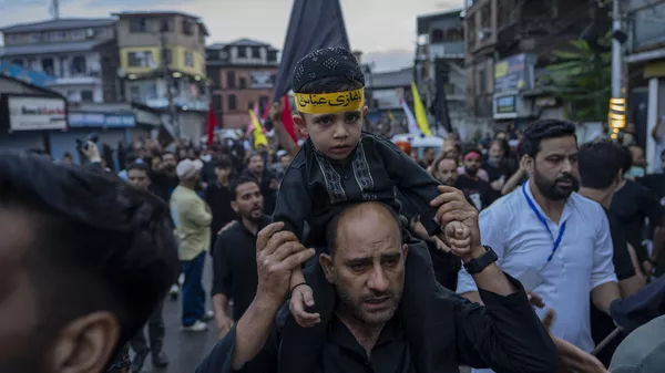 A Kashmiri Shiite Muslim carries his son on his shoulder as they participate in a Muharram procession in Srinagar, Indian controlled Kashmir, Thursday, July 27, 2023. Muharram is a month of mourning for Shiite Muslims in remembrance of the martyrdom of Imam Hussein, the grandson of the Prophet Muhammad.  - Sputnik भारत