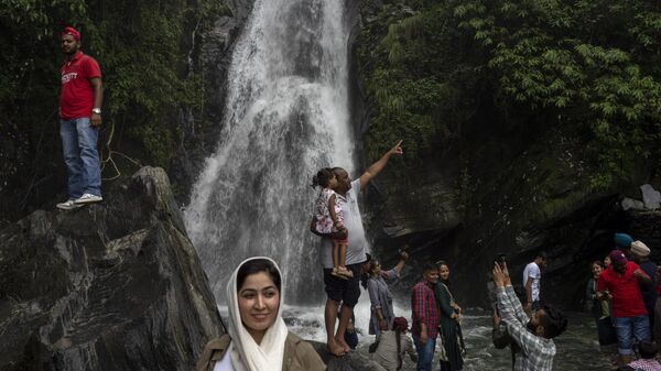 Tourists get their photos taken in front of a waterfall in Dharmsala, India, Tuesday, July 26, 2022. - Sputnik भारत
