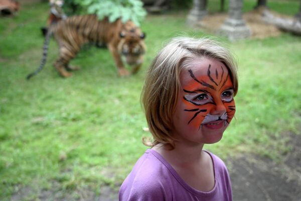 29 जुलाई, 2019 को इंडोनेशिया के रिसॉर्ट द्वीप बाली पर जियान्यार रीजेंसी में सुकावती में बाली चिड़ियाघर में अंतर्राष्ट्रीय बाघ दिवस के अवसर पर बाघ की तरह रंगे चेहरे के साथ एक आगंतुक बाघ के बाड़े के सामने पोज़ देती है। (Photo by SONNY TUMBELAKA / AFP) - Sputnik भारत