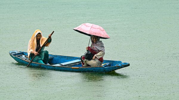 Женщина, прикрывшись тканью, гребет на лодке по озеру Дал во время дождя в Сринагаре - Sputnik भारत