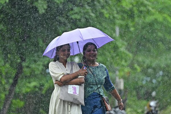 25 जुलाई, 2023 को चेन्नई में बारिश के बीच खुद को बचाने के लिए महिलाएं छाते का इस्तेमाल कर रही हैं। (Photo by R.Satish BABU / AFP) - Sputnik भारत