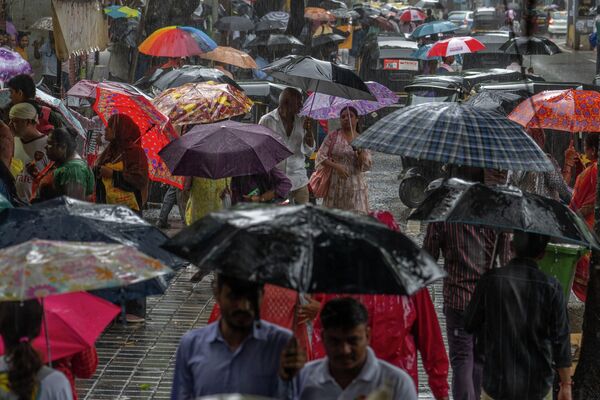 बुधवार, 26 जुलाई, 2023 को भारत के मुंबई में बारिश होने पर लोग छाते पकड़कर चल रहे हैं। (AP Photo/Rafiq Maqbool) - Sputnik भारत