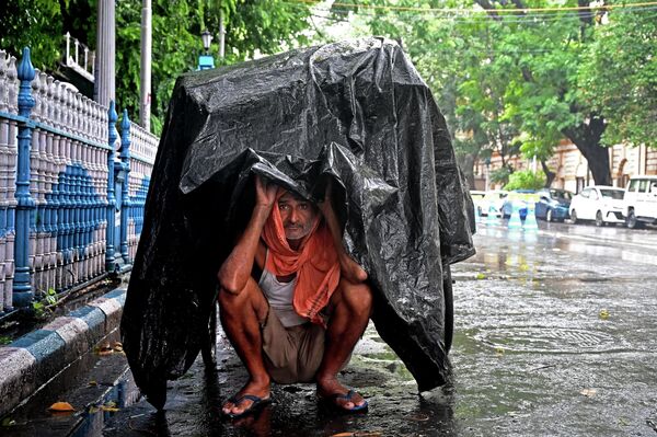 25 जुलाई, 2023 को कोलकाता में बारिश के दौरान खुद को बचाने के लिए एक व्यक्ति प्लास्टिक शीट के नीचे शरण लेता है।(Photo by DIBYANGSHU SARKAR / AFP) - Sputnik भारत