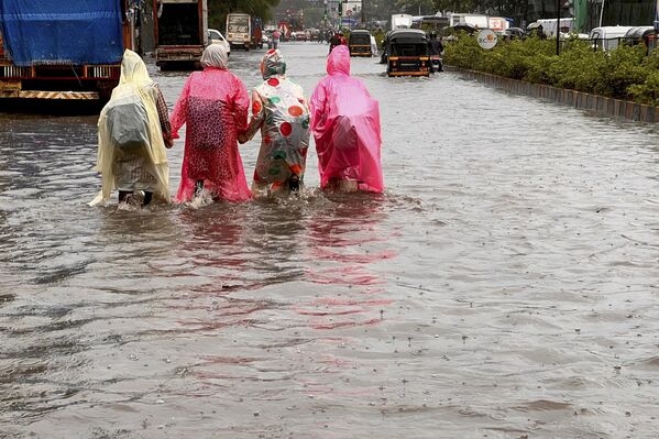 21 जुलाई, 2023 को मुंबई में भारी मानसूनी बारिश के बाद स्कूली बच्चे पानी से भरी सड़क से गुजर रहे थे।(Photo by INDRANIL MUKHERJEE / AFP) - Sputnik भारत
