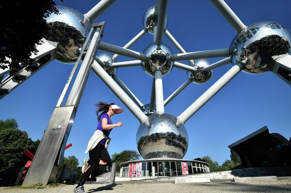 A jogger runs past the Atomium in Brussels on May 20, 2020. - Sputnik India