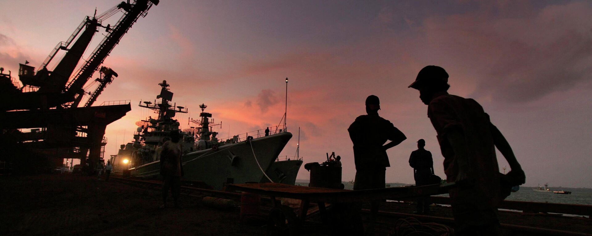 A laborer works at the port as Indian navy warship Mysore lies docked, rear, in Goa, India, Wednesday, Sept. 28, 2005.  - Sputnik भारत, 1920, 29.10.2023