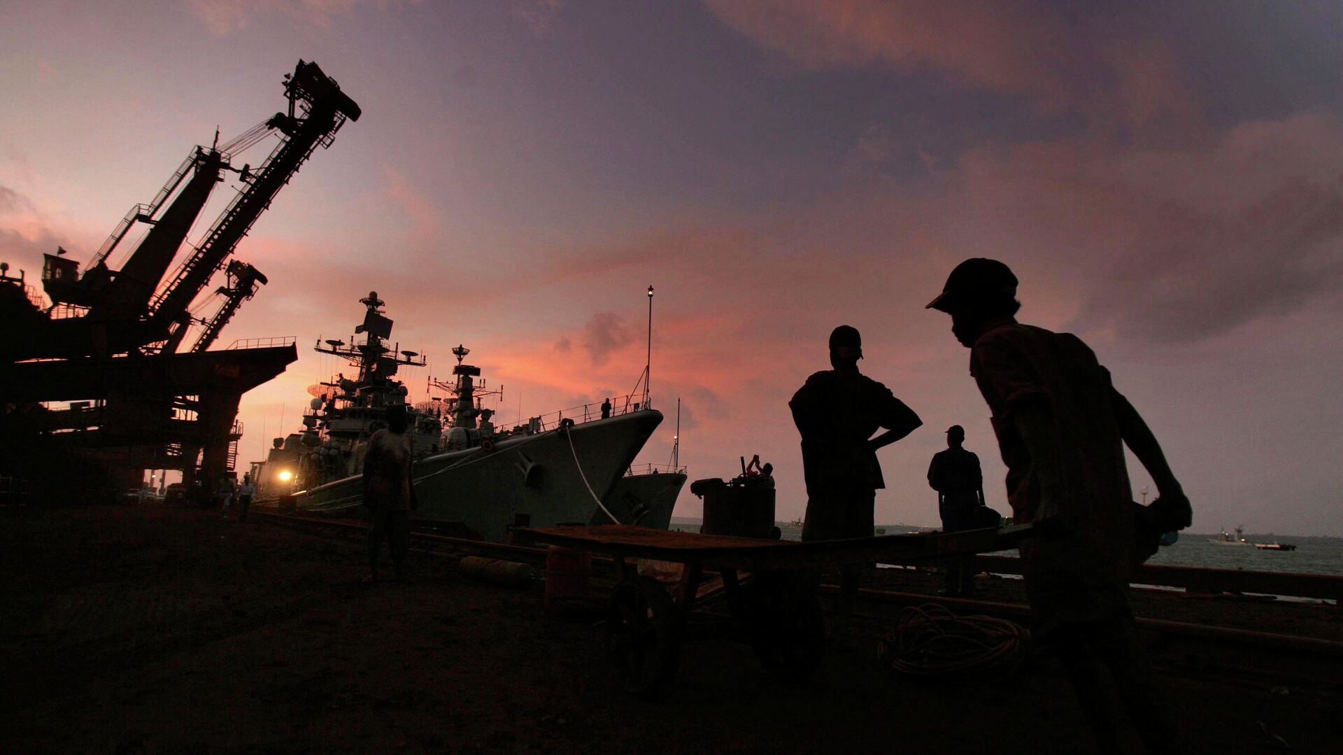 A laborer works at the port as Indian navy warship Mysore lies docked, rear, in Goa, India, Wednesday, Sept. 28, 2005.  - Sputnik भारत, 1920, 29.10.2023