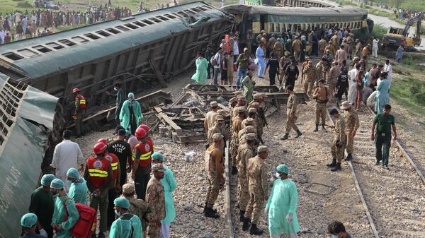 Paramilitary rangers and volunteers inspect the carriages at the accident site following the derailment of a passenger train in Nawabshah on August 6, 2023. At least 19 people were killed and dozens injured on August 6 when an express train derailed in southern Pakistan, government officials said.  - Sputnik भारत