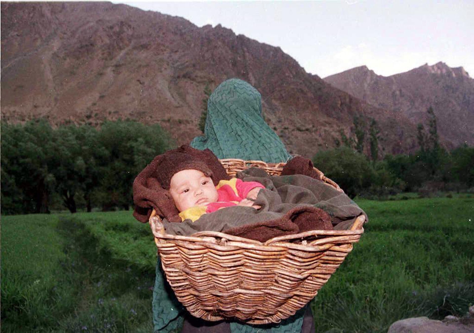 A mother carrying her child flees from her village, Minji, near Kargil, 26 May 1999, where shelling has disrupted normal life. - Sputnik भारत, 1920, 07.08.2023