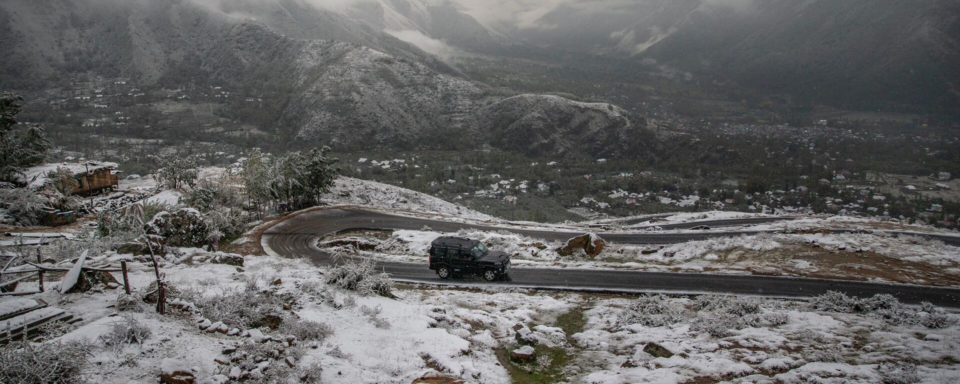A vehicle drives on a road in a snow-covered terrain on the outskirts of Srinagar, Indian controlled Kashmir, Saturday, Oct. 23, 2021. - Sputnik India, 1920, 29.08.2023