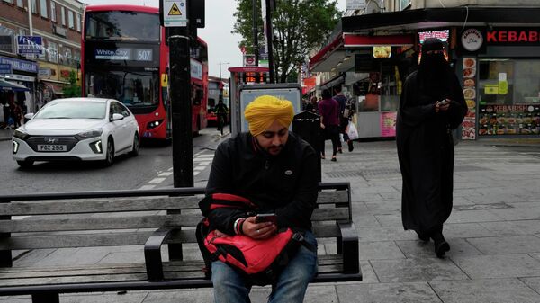 A man sits on a bench in the district of Southall in London - Sputnik भारत
