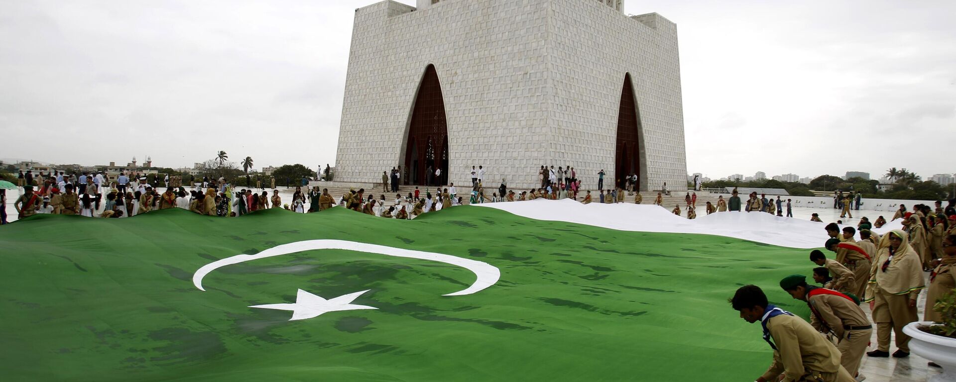 Students hold a giant representation of a Pakistani flag to celebrate the 68th Independence Day at the mausoleum of  Muhammad Ali Jinnah - Sputnik India, 1920, 14.12.2023