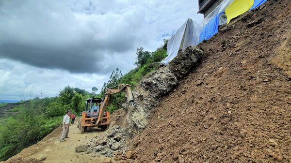 An excavator is being used at the site of a landslide along a road on the outskirts of the northern Indian hilltown of Shimla on July 11, 2023. Days of intense monsoon rains across northern India have left at least 29 people dead, rendering many areas inaccessible with bridges smashed and roads blocked, officials said.  - Sputnik भारत