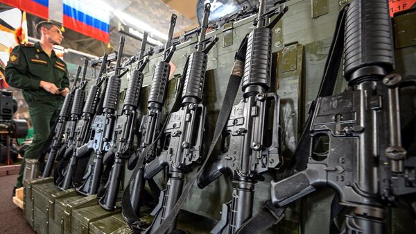 Russian Army Major stands next to captured US assault rifles XM-15 on display at the exposition field in Kubinka Patriot Park outside Moscow on August 15, 2023 during the International Military Forum Army - 2023.  - Sputnik भारत