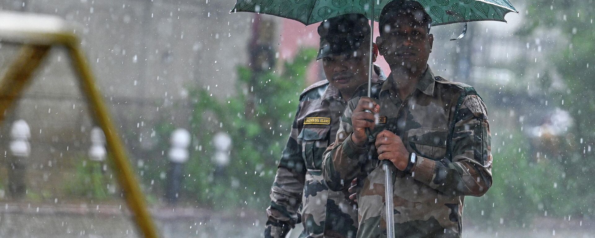 Security personnel use an umbrella to protect themselves amid heavy rainfall in New Delhi on July 18, 2023.  - Sputnik India, 1920, 19.08.2023