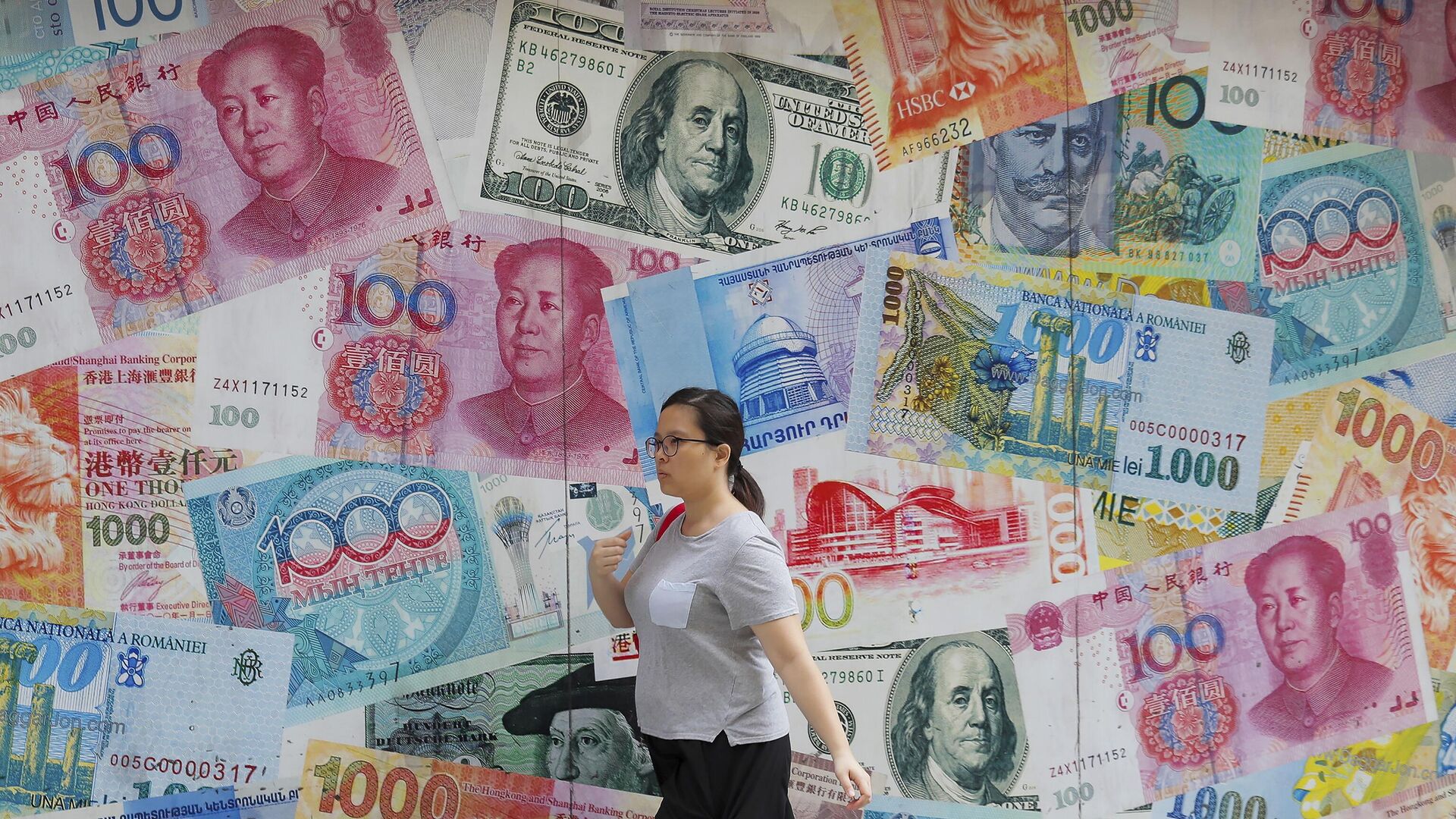 A woman walks by a money exchange shop decorated with banknotes of Chinese yuan and US dollars at Central, a business district in Hong Kong, Tuesday, Aug. 6, 2019. - Sputnik भारत, 1920, 22.08.2023