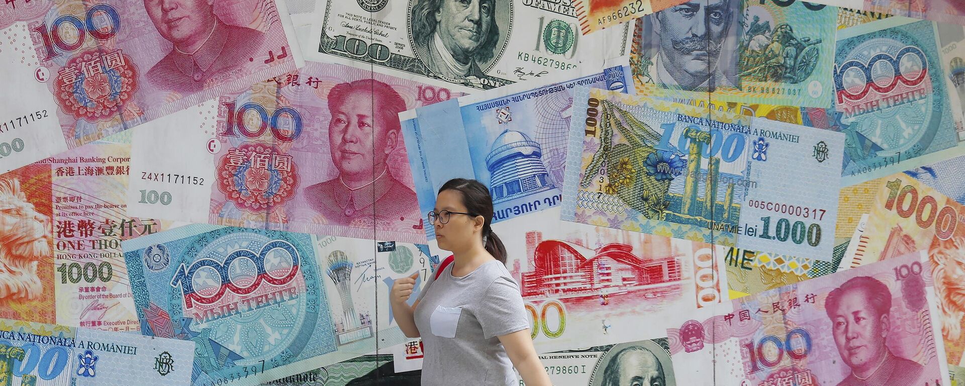 A woman walks by a money exchange shop decorated with banknotes of Chinese yuan and US dollars at Central, a business district in Hong Kong, Tuesday, Aug. 6, 2019. - Sputnik भारत, 1920, 10.12.2024