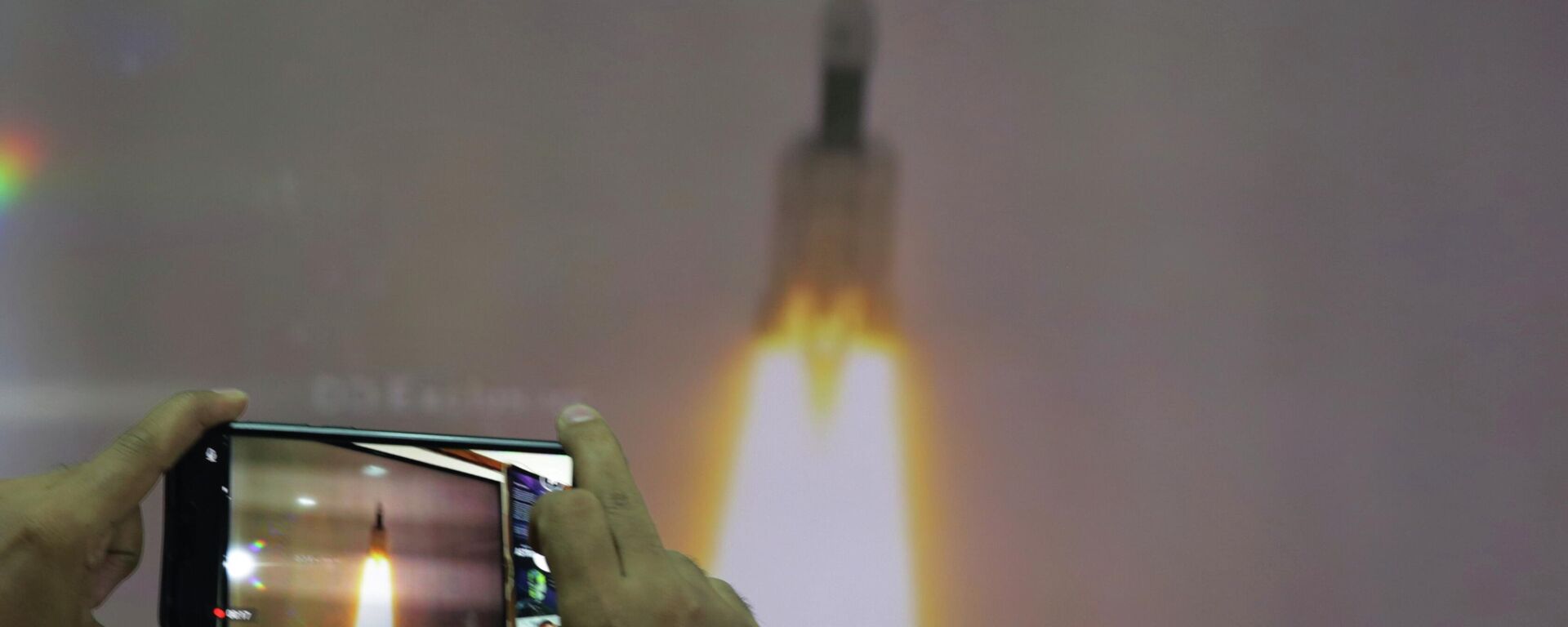 A man at New Delhi's Nehru Planetarium, takes pictures of a web cast of the lift off of Indian Space Research Organization (ISRO)'s Geosynchronous Satellite launch Vehicle (GSLV) MkIII carrying Chandrayaan-2 from Satish Dhawan Space center in Sriharikota, India, Monday, July 22, 2019. - Sputnik India, 1920, 24.08.2023