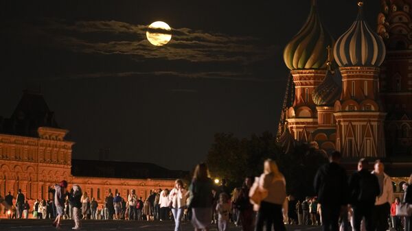 The August Super Blue Moon sets behind a historical building and the St. Basil's Cathedral, right, as people walk in Red Square in Moscow, Russia, Wednesday, Aug. 30, 2023 - Sputnik India