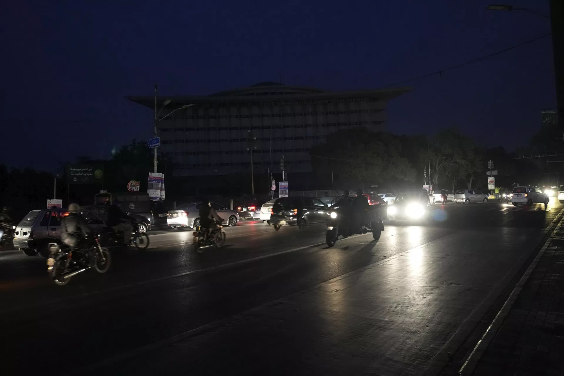 Motorcyclists and cars drive on a road during a national-wide power breakdown, in Lahore, Pakistan, Monday, Jan. 23, 2023. 