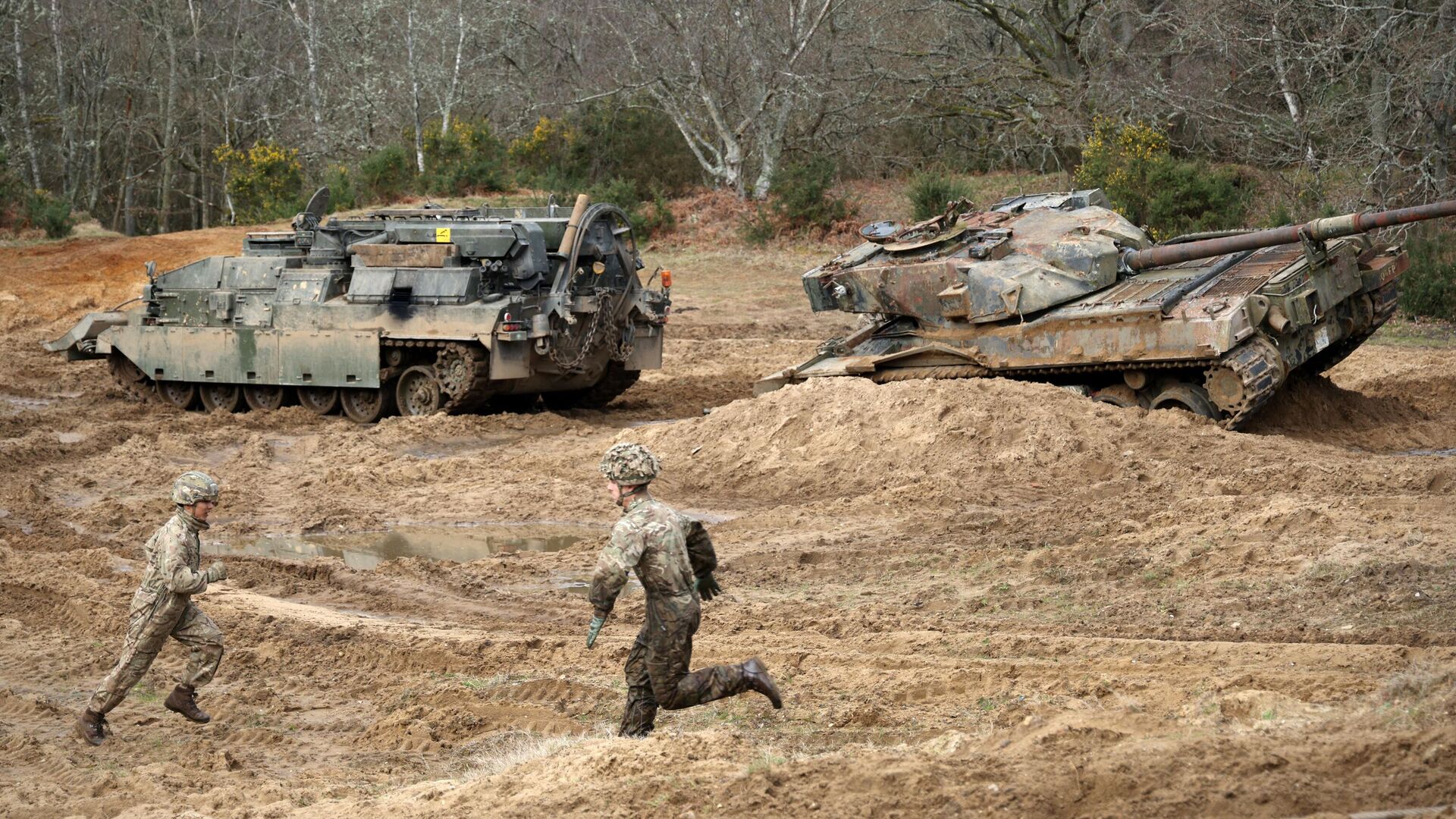 Soldiers run across the training ground as they take part in an exercise to winch an overturned battle tank using a CrARRV (Challenger Armoured Repair and Recovery Vehicle) during the Royal Electrical & Mechanical Engineers’ Exercise called Iron Challenge at the Longmoor training area, near Bordon, Hampshire, on March 14, 2022 - Sputnik भारत, 1920, 06.09.2023