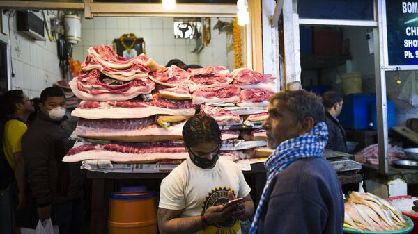 A vendor (C) wearing a facemask, amid concerns over the spread of the COVID-19 novel coronavirus, waits for customers at his meat shop in a market in New Delhi on March 14, 2020.  - Sputnik भारत