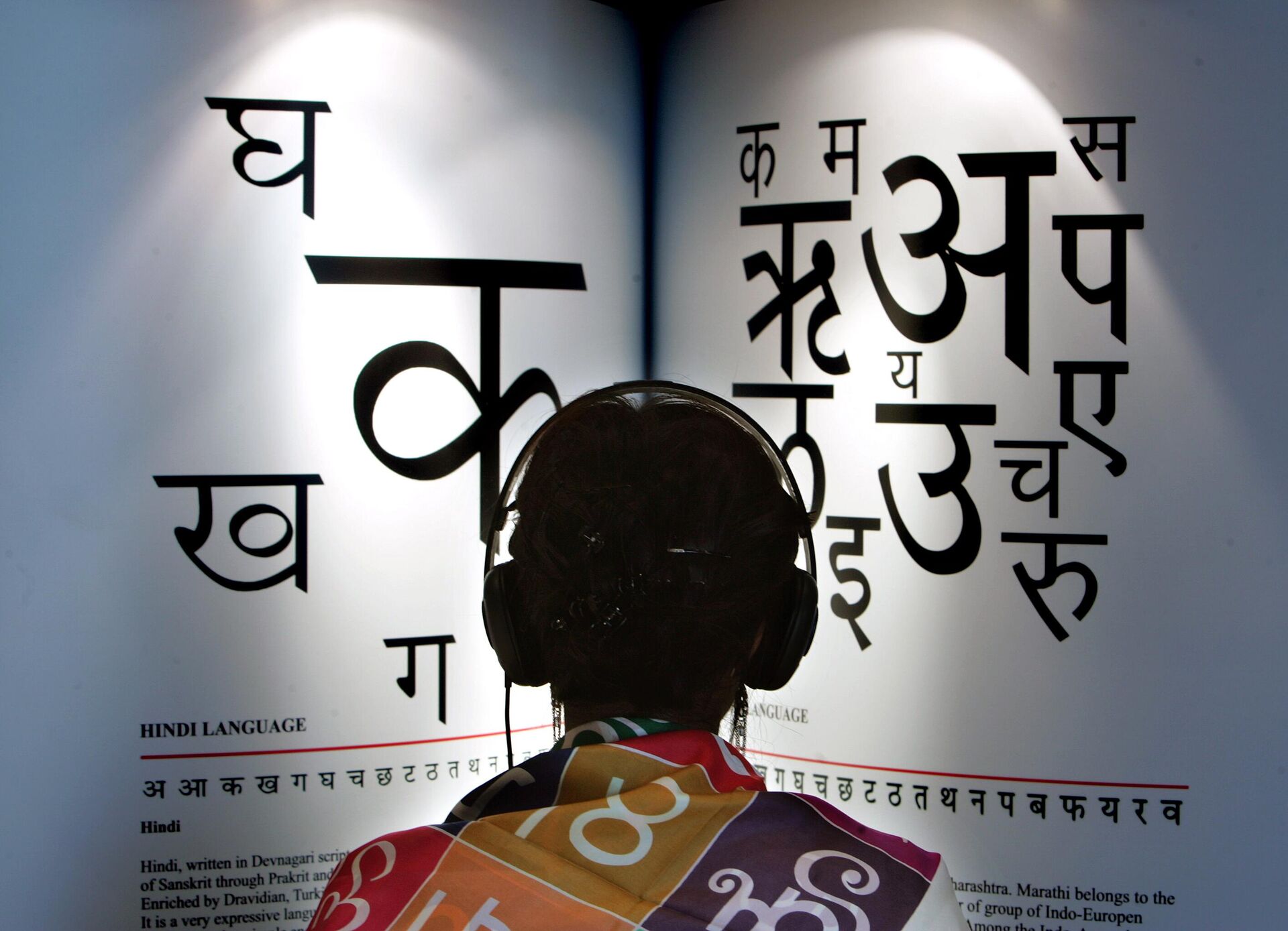 A woman listens to explanations on headphones about the Indian languages Hindi, left, and Marathi at the International Book Fair in Frankfurt, central Germany - Sputnik India, 1920, 10.12.2023