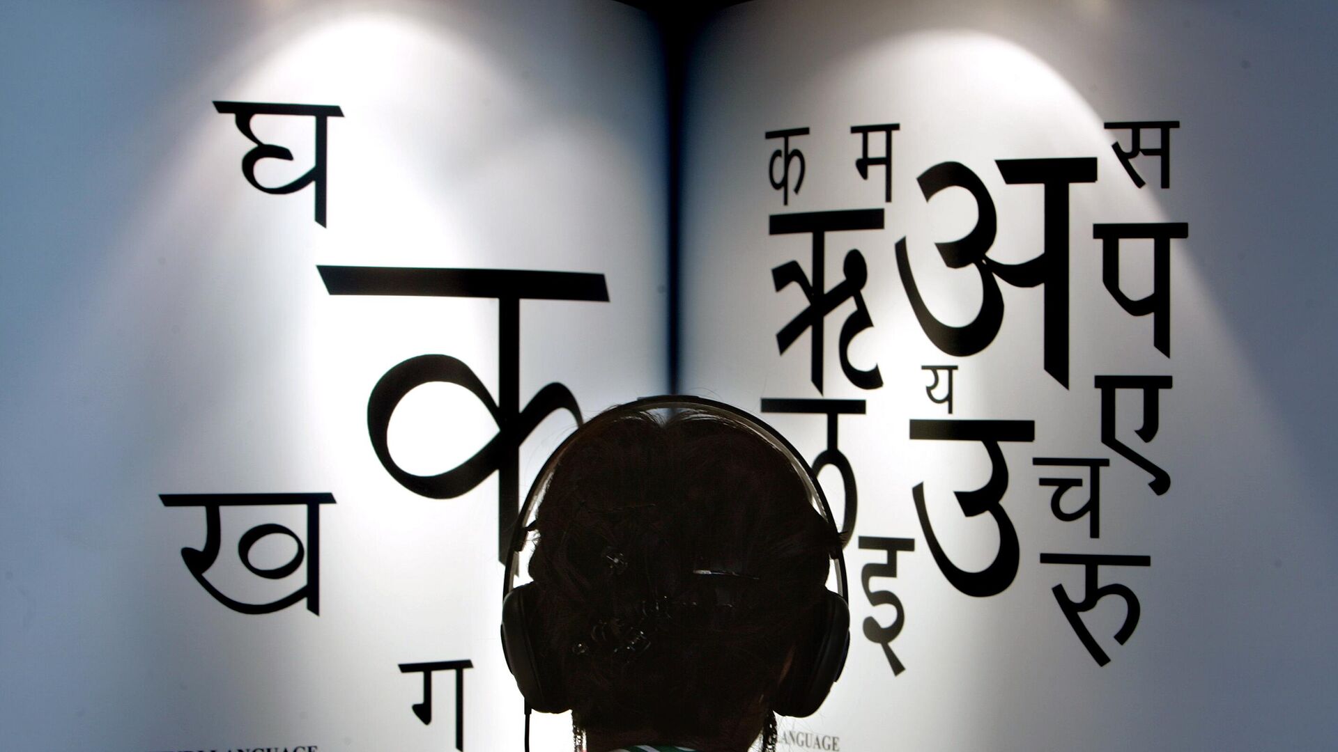 A woman listens to explanations on headphones about the Indian languages Hindi, left, and Marathi at the International Book Fair in Frankfurt, central Germany - Sputnik India, 1920, 14.09.2023