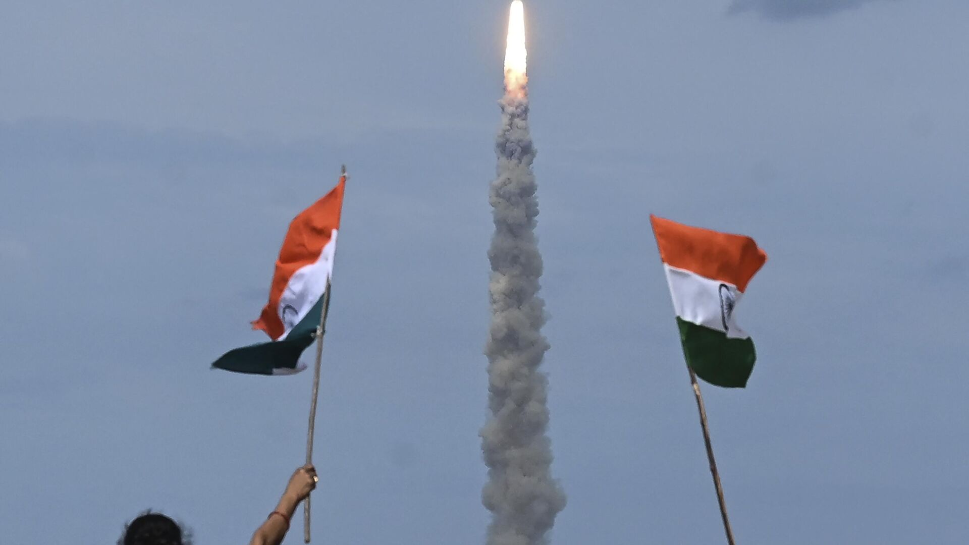People wave Indian flags as an Indian Space Research Organisation (ISRO) rocket carrying the Chandrayaan-3 spacecraft lifts off from the Satish Dhawan Space Centre in Sriharikota, an island off the coast of southern Andhra Pradesh state on July 14, 2023.  - Sputnik भारत, 1920, 11.12.2023