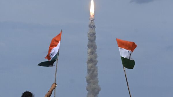 People wave Indian flags as an Indian Space Research Organisation (ISRO) rocket carrying the Chandrayaan-3 spacecraft lifts off from the Satish Dhawan Space Centre in Sriharikota, an island off the coast of southern Andhra Pradesh state on July 14, 2023.  - Sputnik भारत