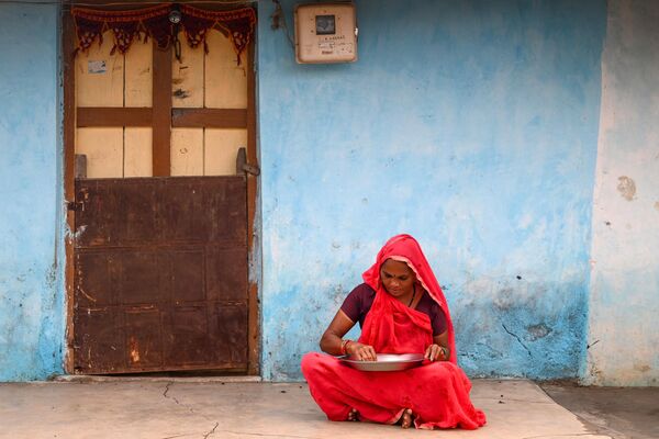 गुजरात के टंकरी बंदर गांव में एक महिला अपने घर में छिले हुए चावल छान रही है।  - Sputnik भारत