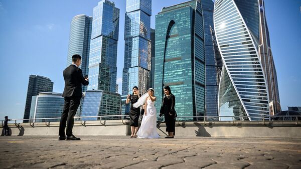 A fiance takes photos of his bride in front of the buildings of Moscow's International Business Centre (Moskva City) in Moscow on September 23, 2023. - Sputnik India