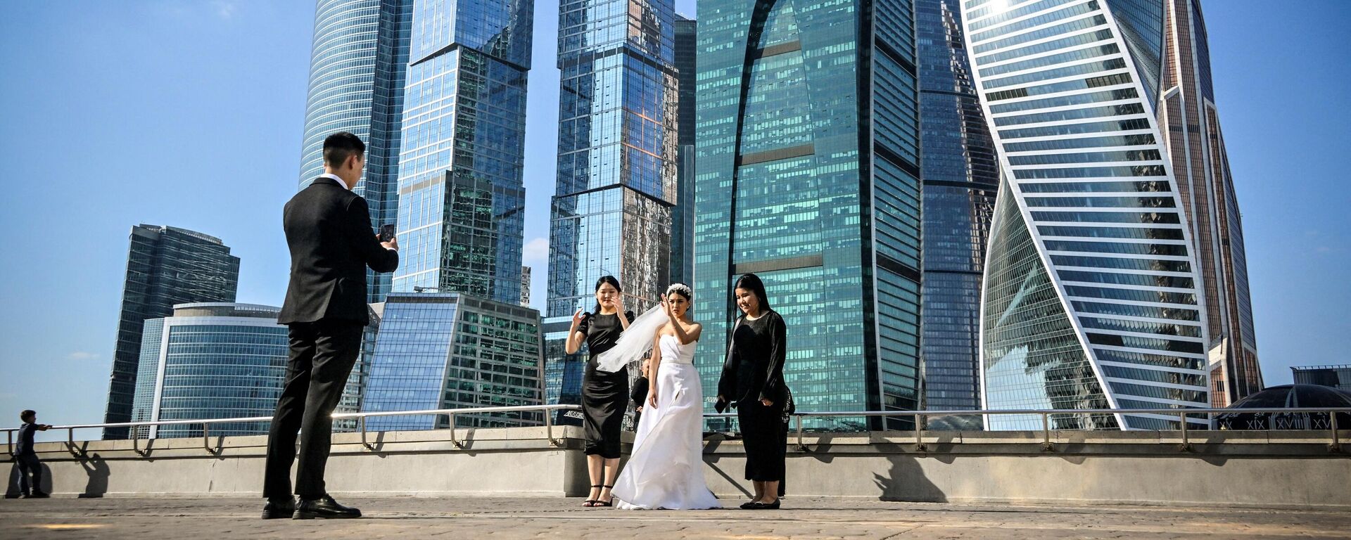 A fiance takes photos of his bride in front of the buildings of Moscow's International Business Centre (Moskva City) in Moscow on September 23, 2023. - Sputnik India, 1920, 01.10.2023