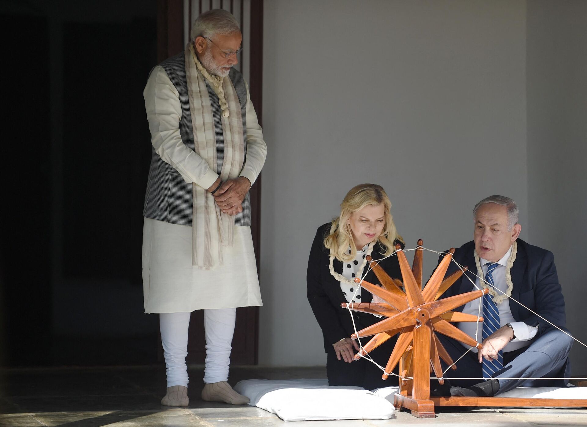 Israeli Prime Minister Benjamin Netanyahu (R) uses a spinning wheel as his wife Sara Netanyahu (C) and Indian Prime Minister Narendra Modi look on during a visit to Gandhi Ashram in Ahmedabad on January 17, 2018. - Sputnik भारत, 1920, 09.10.2023