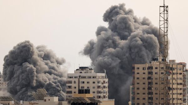 A black plume of smoke billows behind highrise buildings in the sky during an Israeli airstrike on Gaza City on October 9, 2023.  - Sputnik India