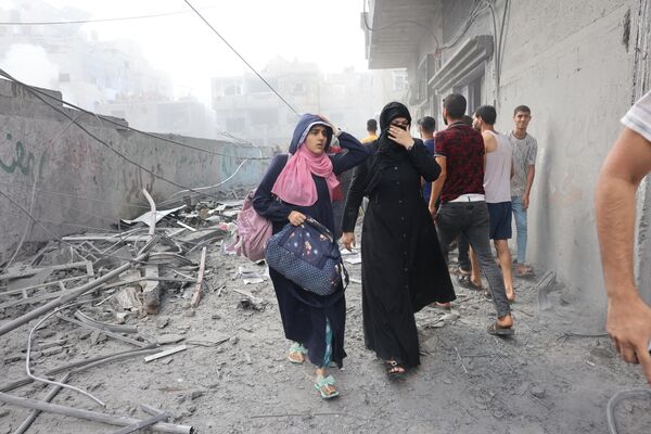 Women flee following an Israeli strike, as battles between Israel and the Hamas movement continue for the sixth consecutive day, in the city Rafah, in the southern Gaza Strip on 12 October 2023. (SAID KHATIB / AFP) - Sputnik India