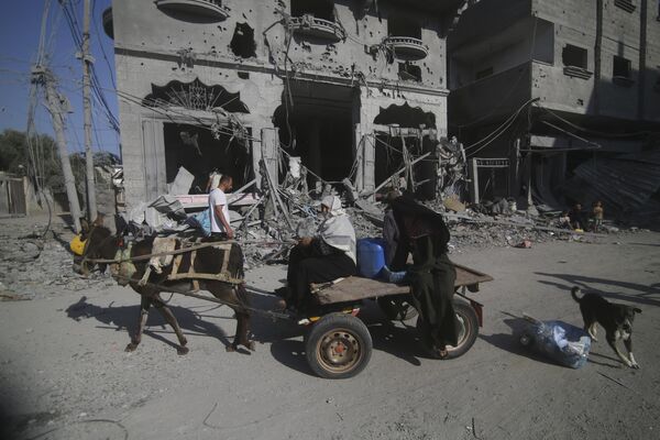 Palestinians leave their houses following Israeli airstrikes in the Rafah refugee camp, southern Gaza Strip, Thursday, 12 October 2023. (AP Photo/Hatem Ali) - Sputnik India