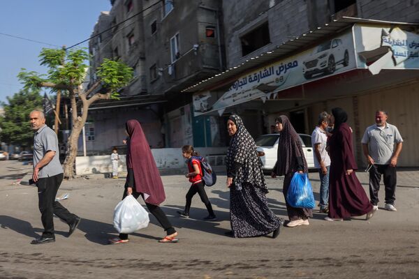 Palestinians carrying their belongings flee to safer areas in Gaza City after Israeli air strikes, on 13 October 2023. (MOHAMMED ABED / AFP) - Sputnik India