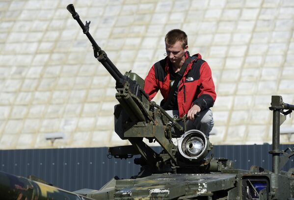 पकड़े गए यूक्रेन के सशस्त्र बलों के सैन्य उपकरण की प्रदर्शनी के दौरान  एक टैंक पर एक व्यक्ति। - Sputnik भारत
