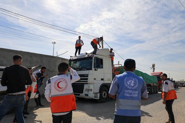 सहायता कर्मी मानवीय सहायता ले जाने वाले ट्रकों के आसपास इकट्ठा होते हैं जो 21 अक्टूबर, 2023 को राफा सीमा पार के माध्यम से मिस्र से गाजा पट्टी में प्रवेश कर गए हैं।(Photo by SAID KHATIB / AFP) - Sputnik भारत