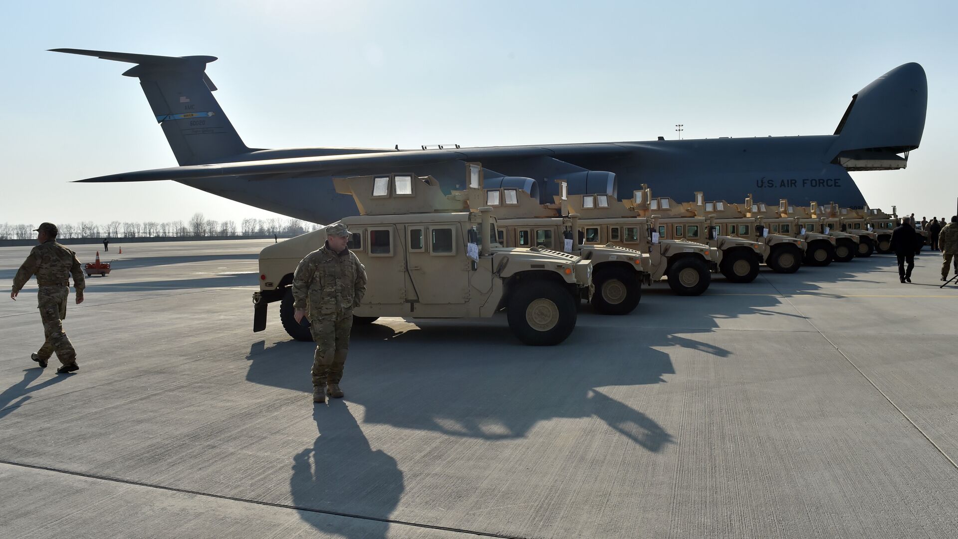 Ukrainian servicemen walk in front of armoured cars at Kiev airport on March 25, 2015 during a welcoming ceremony of the first US plane delivery of non-lethal aid, including 10 Humvee vehicles. - Sputnik भारत, 1920, 22.10.2023